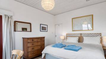 Ein Schlafzimmer mit Bett, Kommode, Stuhl und einer Hängeleuchte.