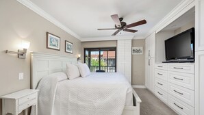 A bedroom with a bed, a ceiling fan, a TV, and a sliding door to a balcony. - Gorgeous Partial Beach View 3 bed, 2 bath at Sanibel Moorings #532 (Sanibel)