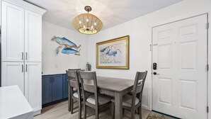 Un coin repas avec une table et des chaises en bois, un lustre et des œuvres d’art accrochées aux murs.