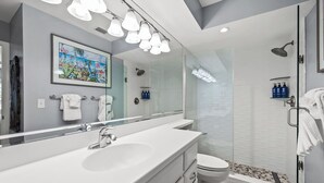 Une salle de bain moderne avec un grand miroir, un lavabo, des toilettes et un espace douche.