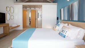 A modern hotel room with a large bed, a wooden headboard, a TV, and a view of the hallway. - Villa Sivota, Exclusive sea front Villa with 99" Underground Cinema (Sivota)