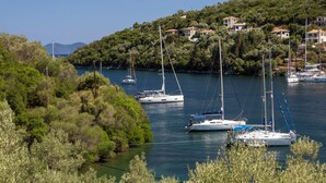 A coastal area with multiple sailboats docked near a densely forested hillside with houses. - Villa Sivota, Exclusive sea front Villa with 99" Underground Cinema (Sivota)