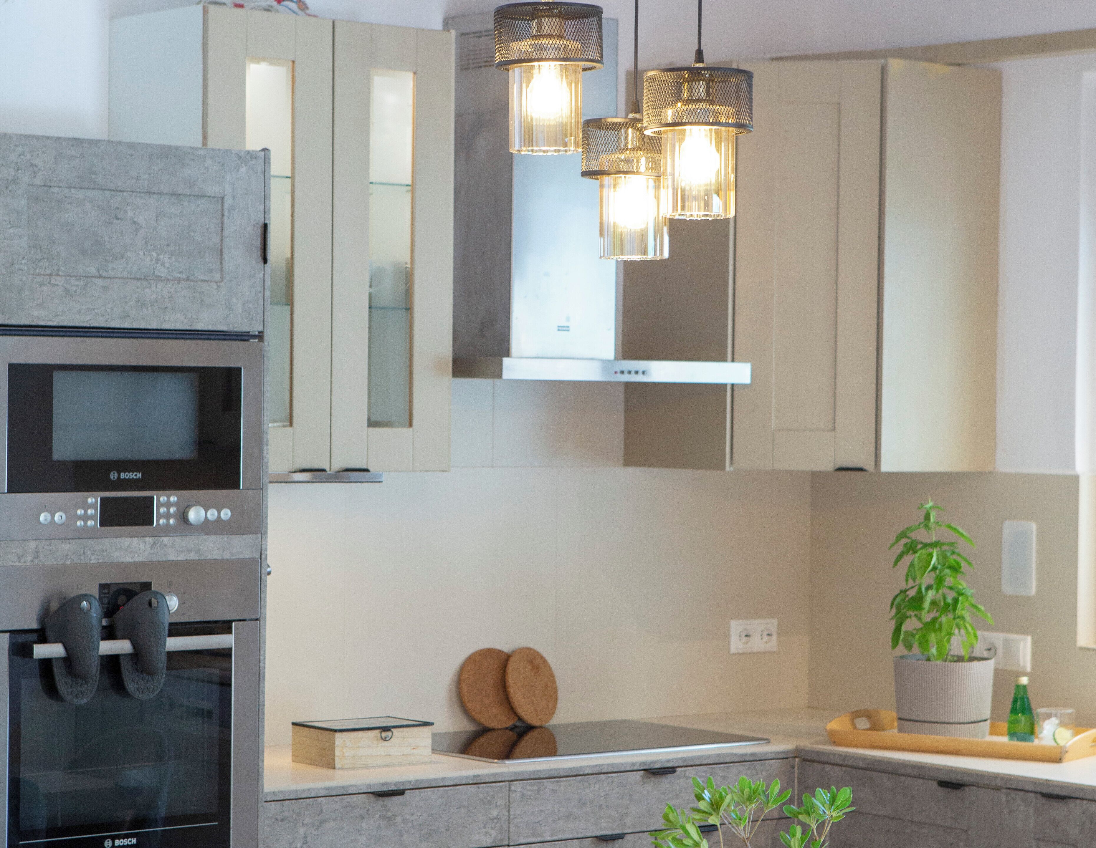 Una cocina moderna con horno Bosch, armarios de acero inoxidable e iluminación colgante.