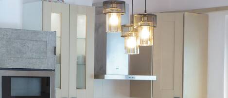 Una cocina moderna con horno Bosch, armarios de acero inoxidable e iluminación colgante.