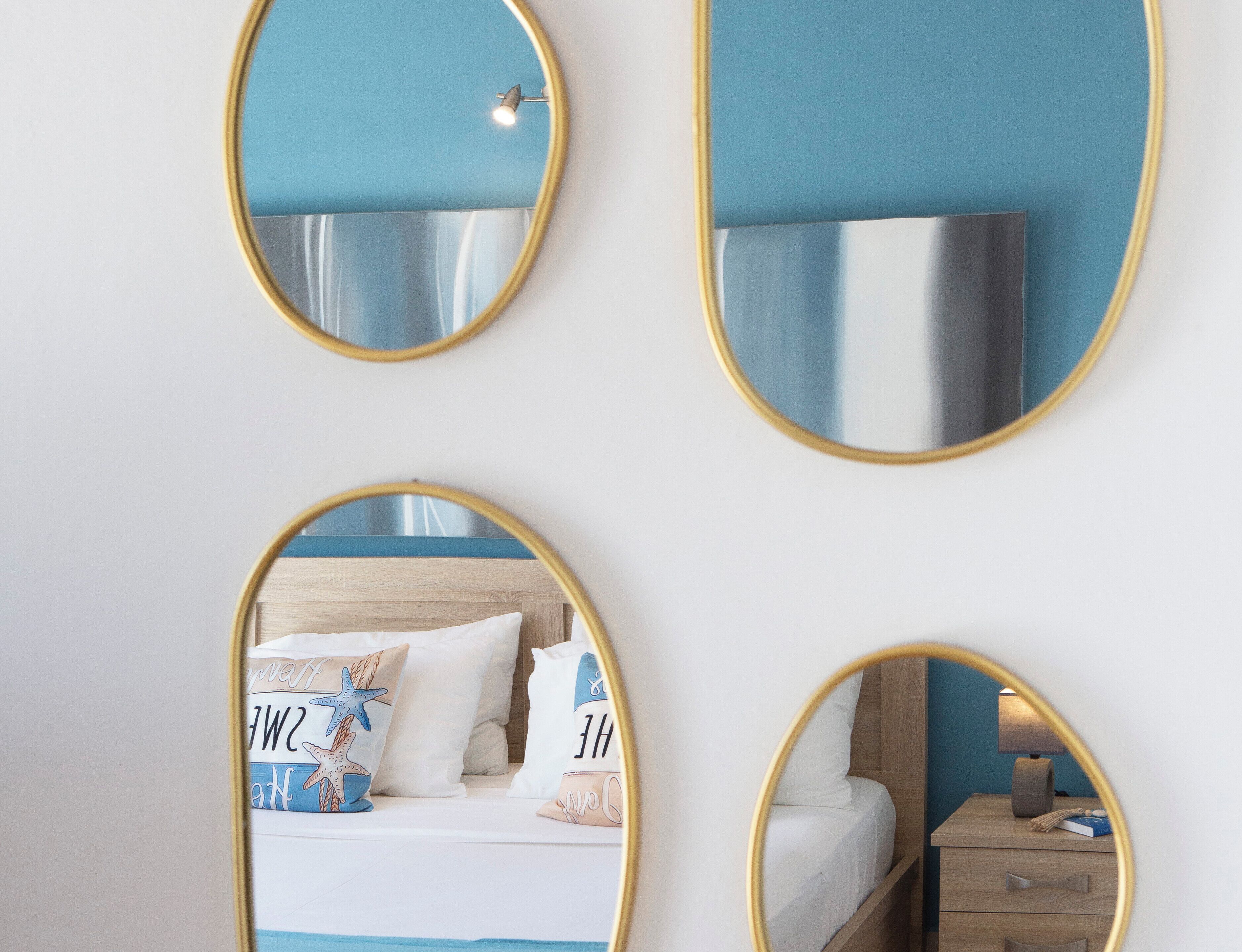 Un dormitorio con cama, mesita de noche y un espejo que refleja la habitación.