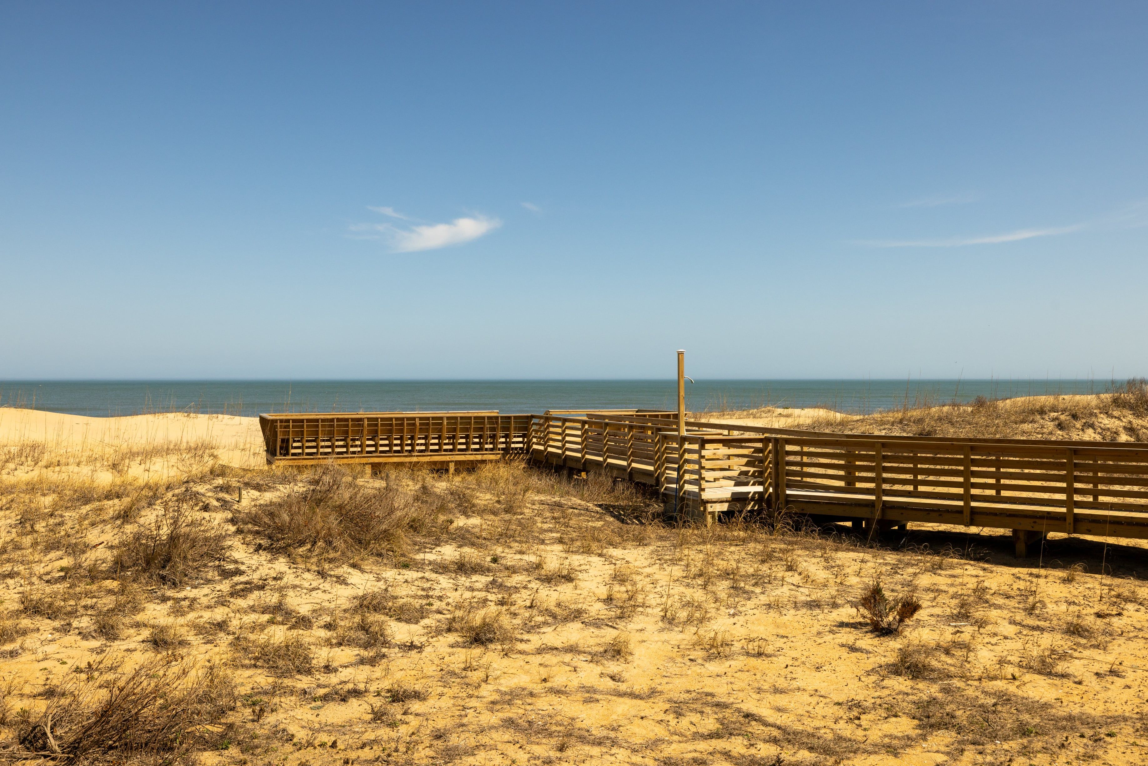 Una spiaggia sabbiosa con passerelle in legno e una vista limpida sull'oceano.
