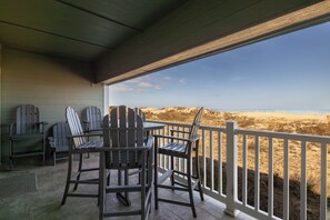 Un espacio de estar al aire libre cubierto con sillas Adirondack y vistas a la playa.