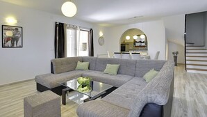 A modern living room with a sectional sofa, a glass coffee table, and a dining area in the background. - Comfortable villa just 1,5 km from beach with private pool (Medulin)