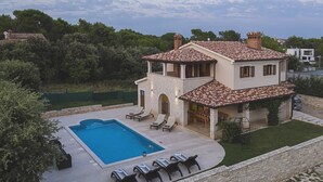 A two-story house with a swimming pool, outdoor seating, and a stone wall surrounding the property. - Comfortable villa just 1,5 km from beach with private pool (Medulin)