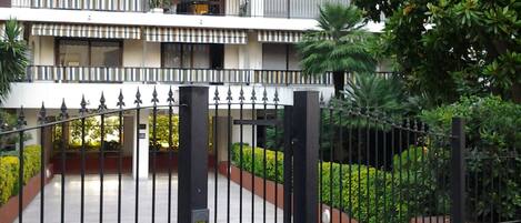Una entrada cerrada con portón de metal y teclado electrónico a un edificio de diseño moderno.