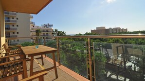 A balcony with a wooden table and chairs, overlooking a residential area with buildings and greenery. - HomeHolidaysRentals Solmar - Costa Barcelona (Santa Susana)