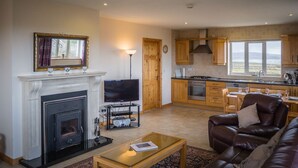 A living room with a fireplace, television, and leather sofa. - Atlantic Sunset,  Aughris is a home away from home (Cleggan)