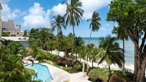A resort with a swimming pool, palm trees, and a beach view. - Modern Beachfront Condo with Pool - Sapphire 211 (Saint Lawrence Gap)