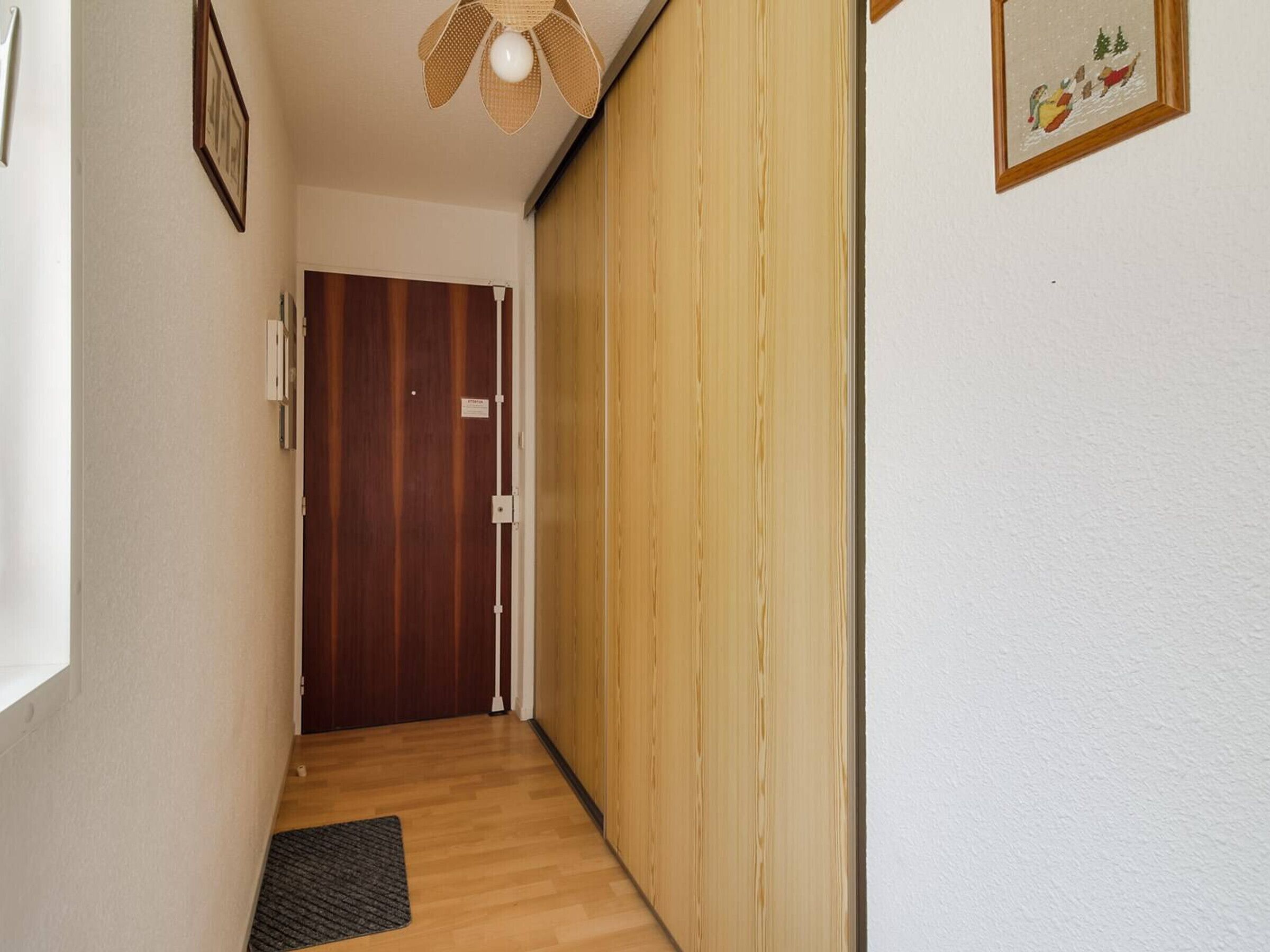 A narrow hallway with wooden flooring, a door at the end, and a ceiling fan.
