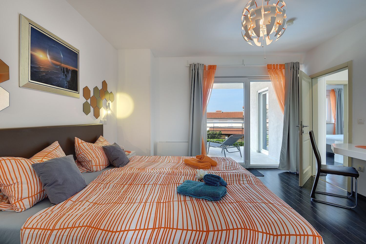 A modern hotel room with a large bed, a view of the outdoors, and a dining area.
