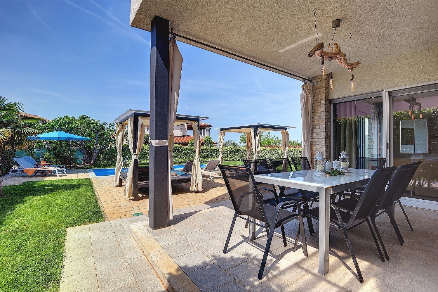Uma área de terraço ao ar livre com mesa, cadeiras, piscina e guarda-sóis.