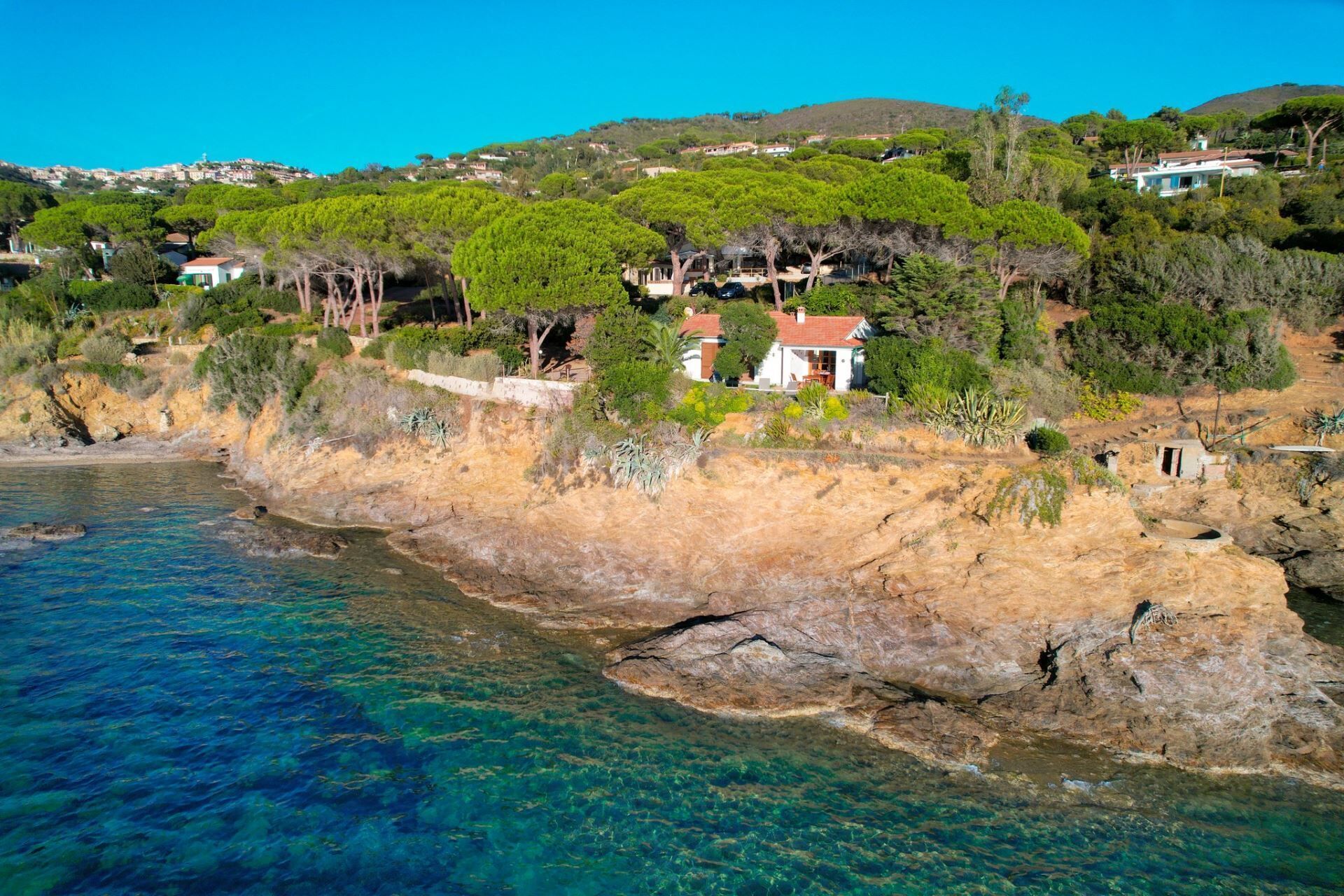 Una proprietà costiera con un litorale roccioso, mare cristallino e vegetazione rigogliosa.
