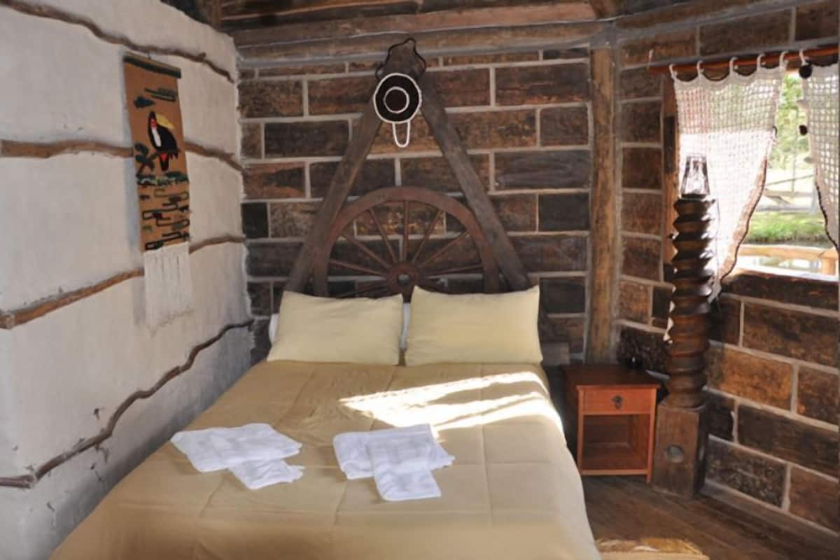 Un lit en bois rustique avec une tête de lit, une petite table de chevet en bois et une horloge fixée au mur.