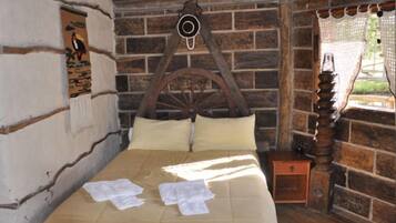 A rustic wooden bed with a headboard, a small wooden nightstand, and a wall-mounted clock.