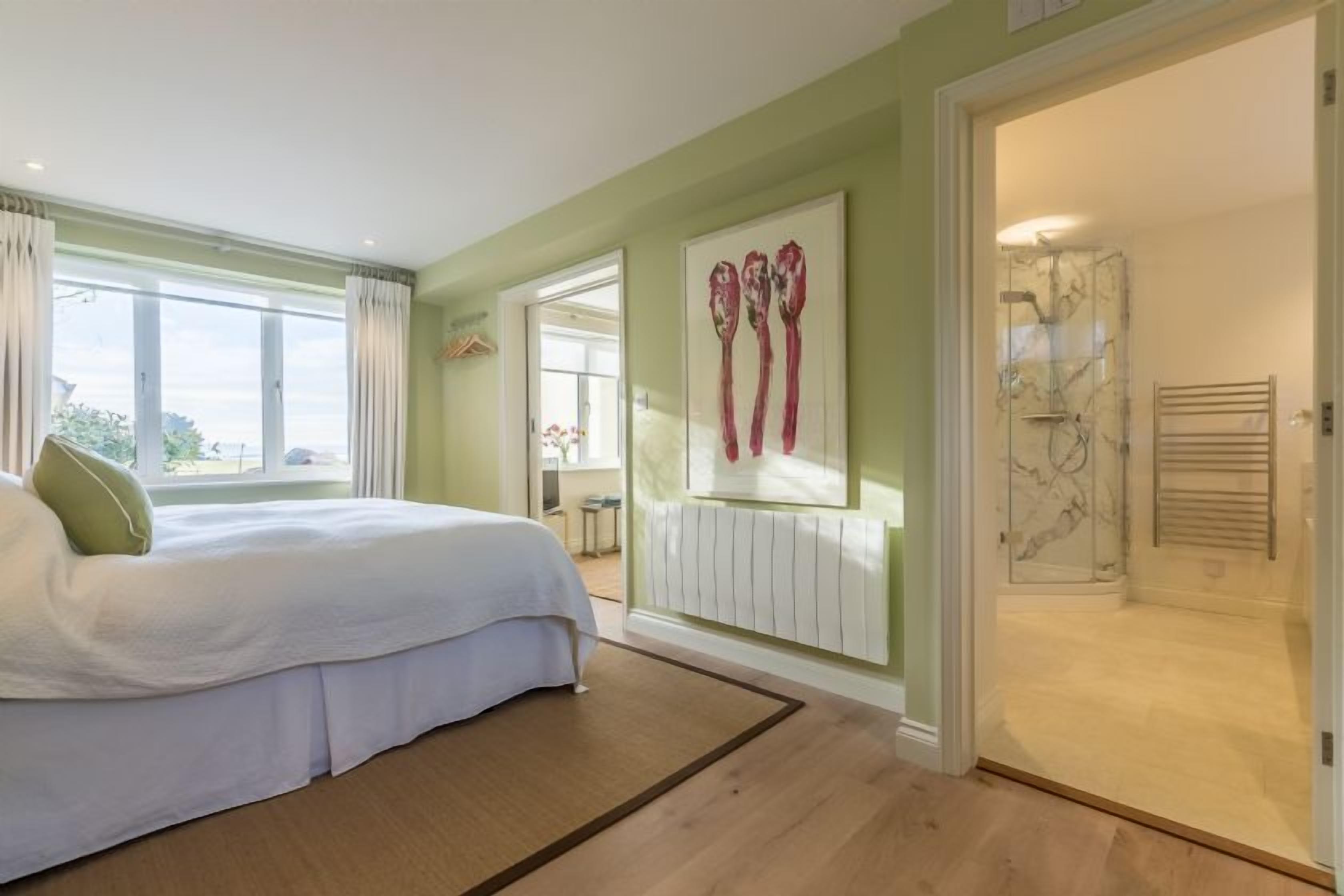 A bedroom with a bed, a radiator, and a shower room.