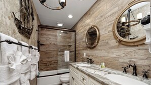 A modern bathroom with a wooden wall, a bathtub, a toilet, and a vanity with a sink and mirrors.
