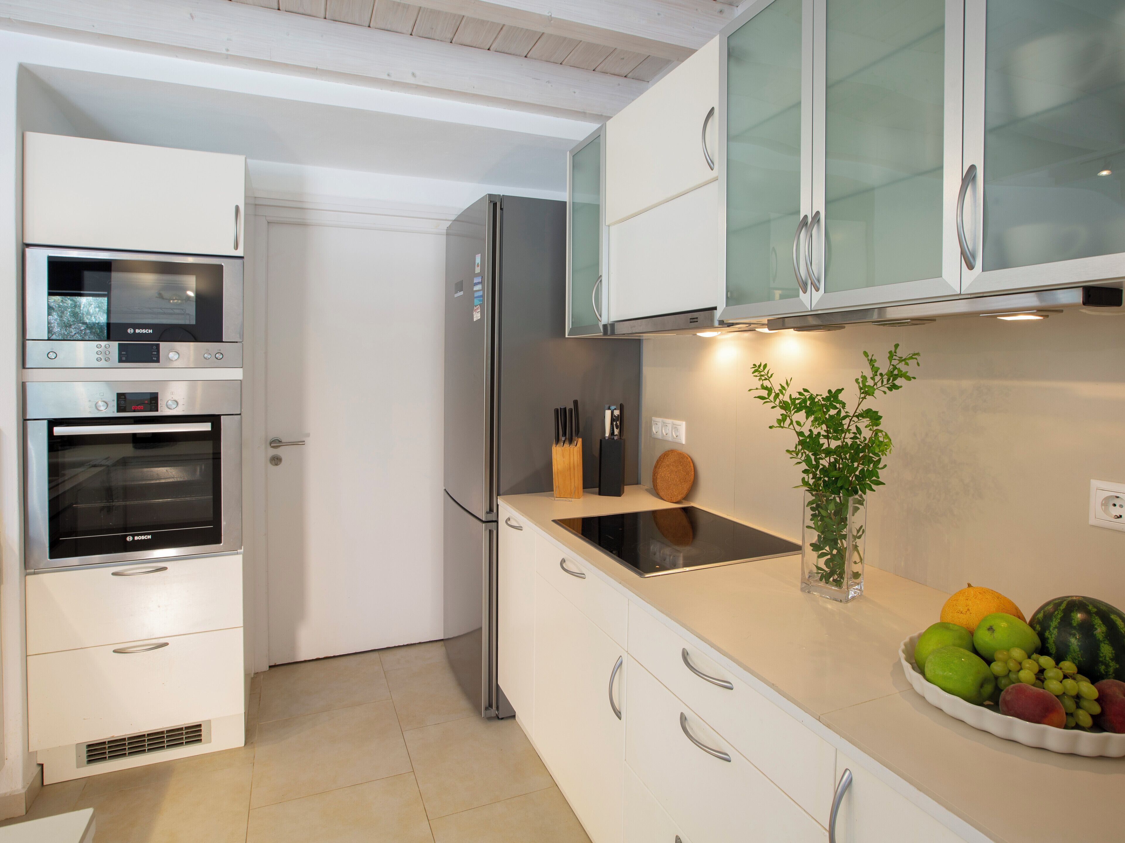 Una cocina moderna con armarios blancos, electrodomésticos de acero inoxidable y un frutero en la encimera.