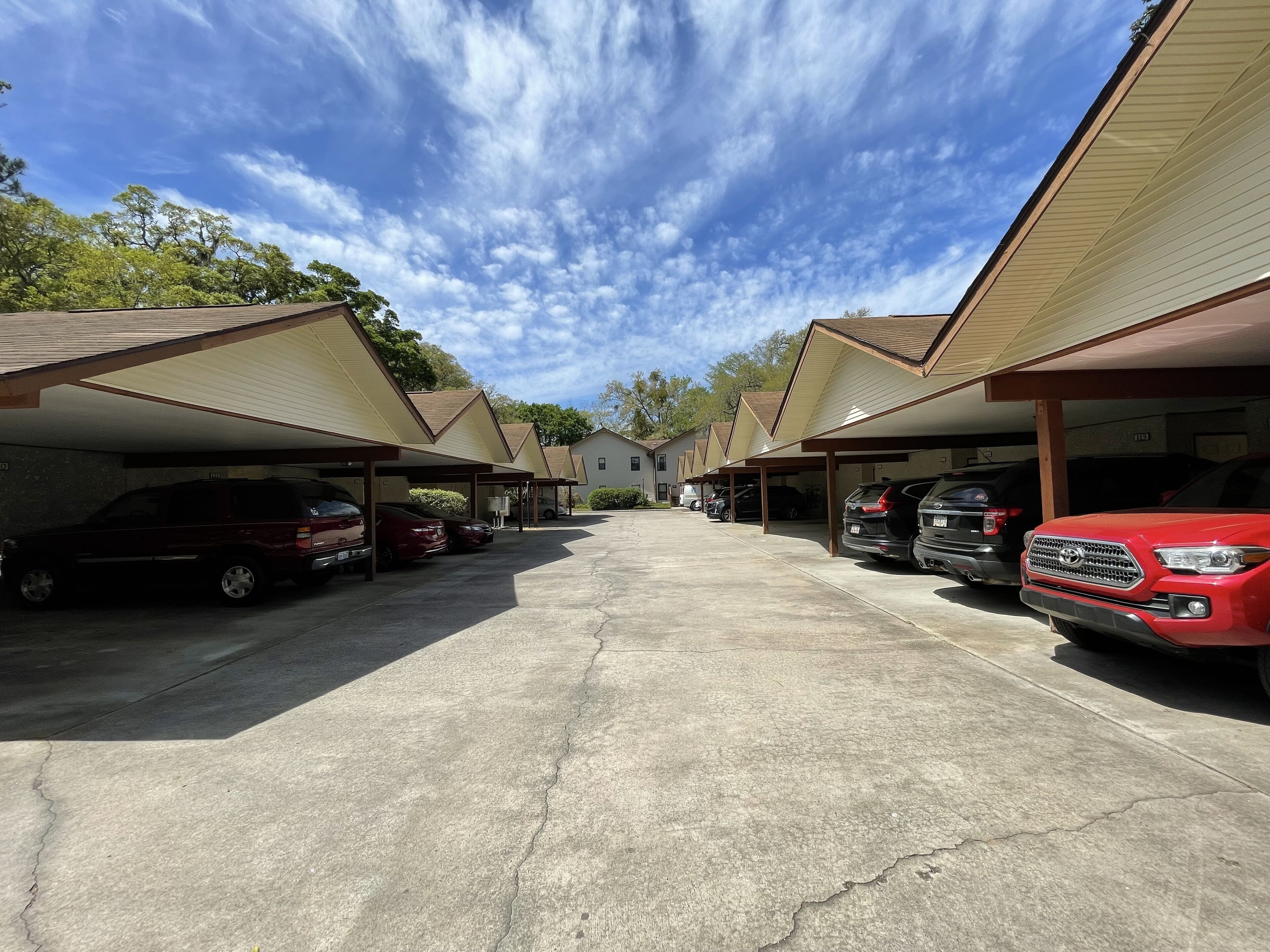 A parking area with covered parking spaces and a building in the background.
