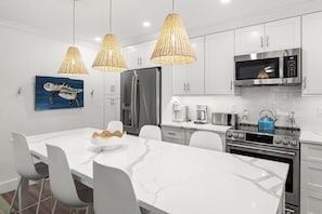 A modern kitchen with white cabinetry, a marble countertop, and stainless steel appliances.