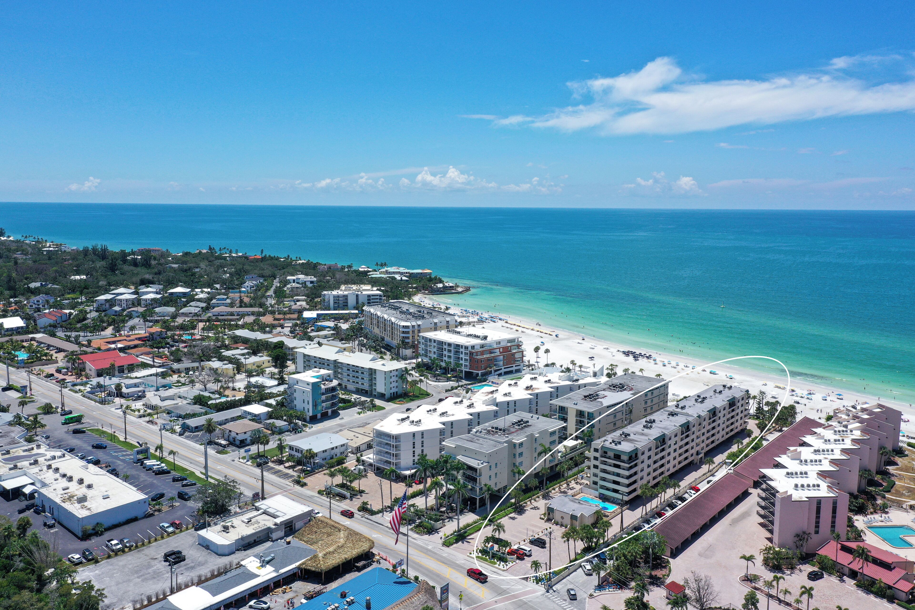 Eine Küstenregion mit Hotels direkt am Strand, blauem Himmel und ruhiger See.