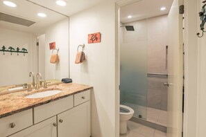 Un baño con lavamanos doble, cabina de ducha con mampara de vidrio y un inodoro.