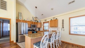 A modern kitchen with wooden cabinets, stainless steel appliances, and a central island with bar stools.