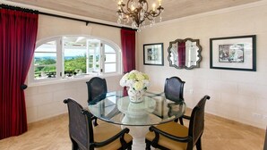 A dining area with a glass table, four chairs, a chandelier, and framed pictures on the wall. - Sunset Views and Private Pool - Sugar Cane 1 (Westmoreland)