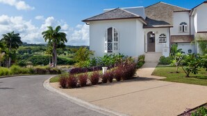 A two-story house with a curved driveway, a front porch, and a view of a lush landscape. - Sunset Views and Private Pool - Sugar Cane 1 (Westmoreland)