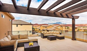 A covered patio with outdoor furniture, a view of neighboring houses, and a mountainous landscape in the background. - 98 - Grand Resort in St George with Private Pool and Rec Court (Santa Clara)