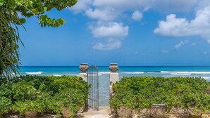 A beach entrance with a gate, lush greenery, and a view of the ocean. - Enchanting Beachfront Retreat - Leamington Cottage (Battaleys)