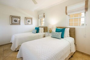 A hotel room with two beds, a nightstand, a lamp, and two framed pictures on the wall.