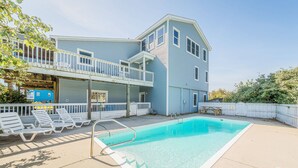 Un bâtiment à deux étages doté d’une piscine, d’un patio couvert et d’une clôture blanche.