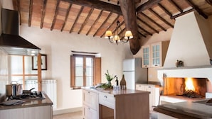 A kitchen with a central island, wooden ceiling beams, and a built-in wood stove. - Montestigliano, an authentic farmhouse in the heart of Tuscany, is an oasis of peace and beauty that offers its guests refined residences and an enchanting view (Rosia - Sovicille)