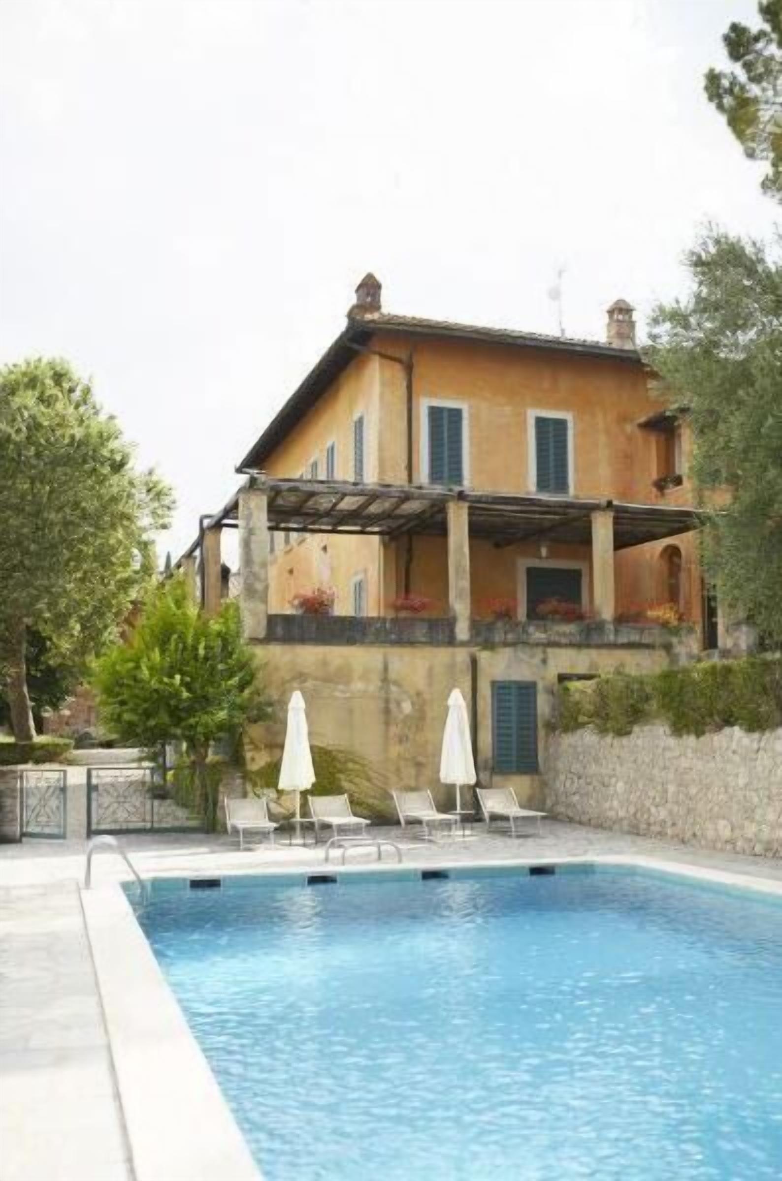 Un bâtiment à deux étages doté d’une piscine, d’un espace extérieur aménagé et d’un mur en pierre.