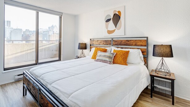 Un dormitorio moderno con una cama grande, vistas a la ciudad y una decoración minimalista.