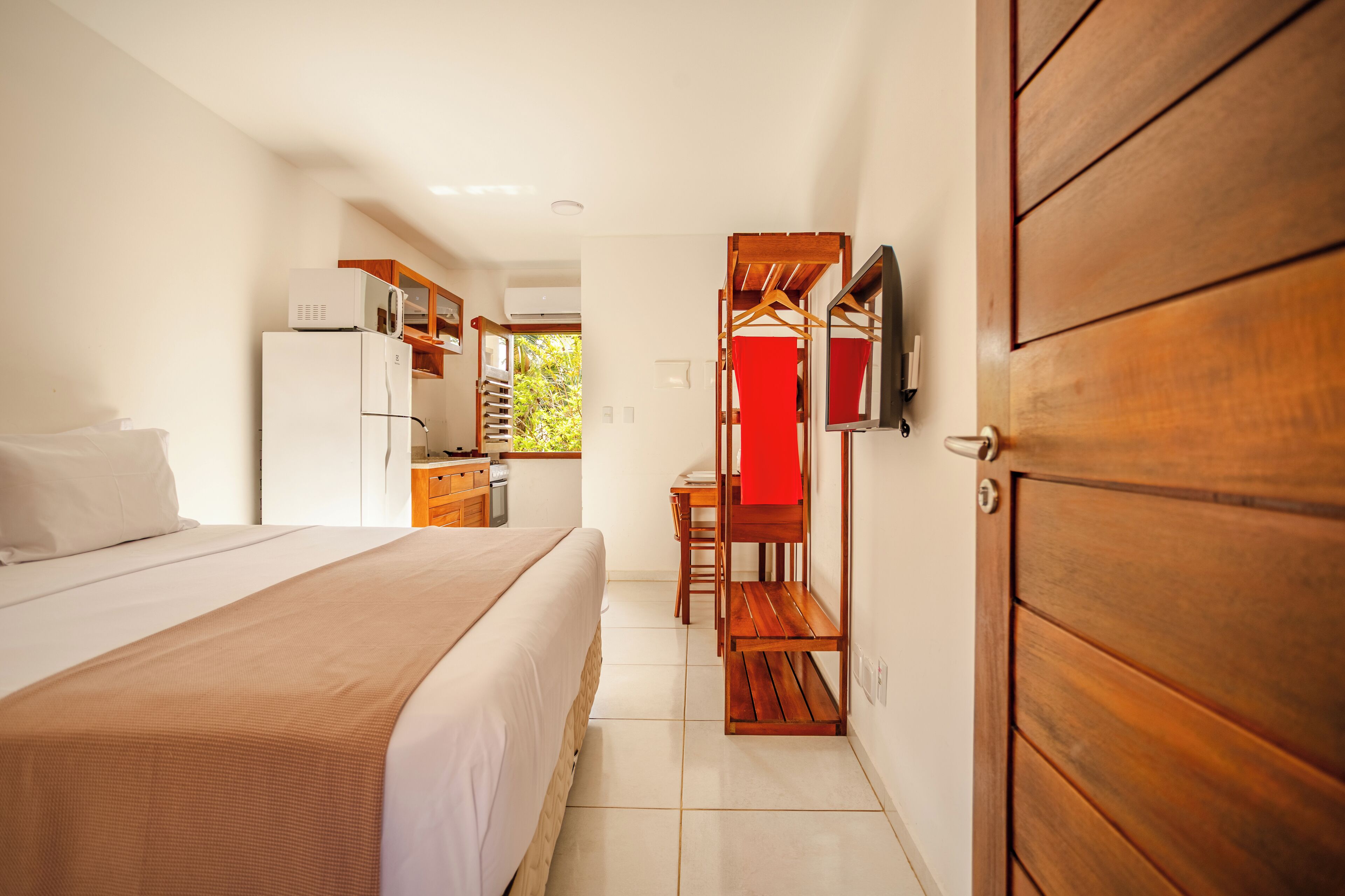 Una habitación de hotel con cama, escritorio, armario y kitchenette.
