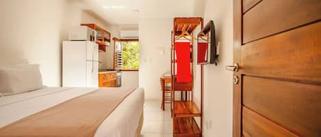 Una habitación de hotel con cama, escritorio, armario y kitchenette.