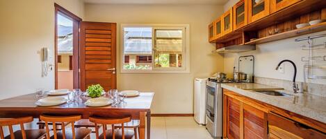 A compact kitchen with wooden cabinets, a built-in oven, and a window overlooking greenery.