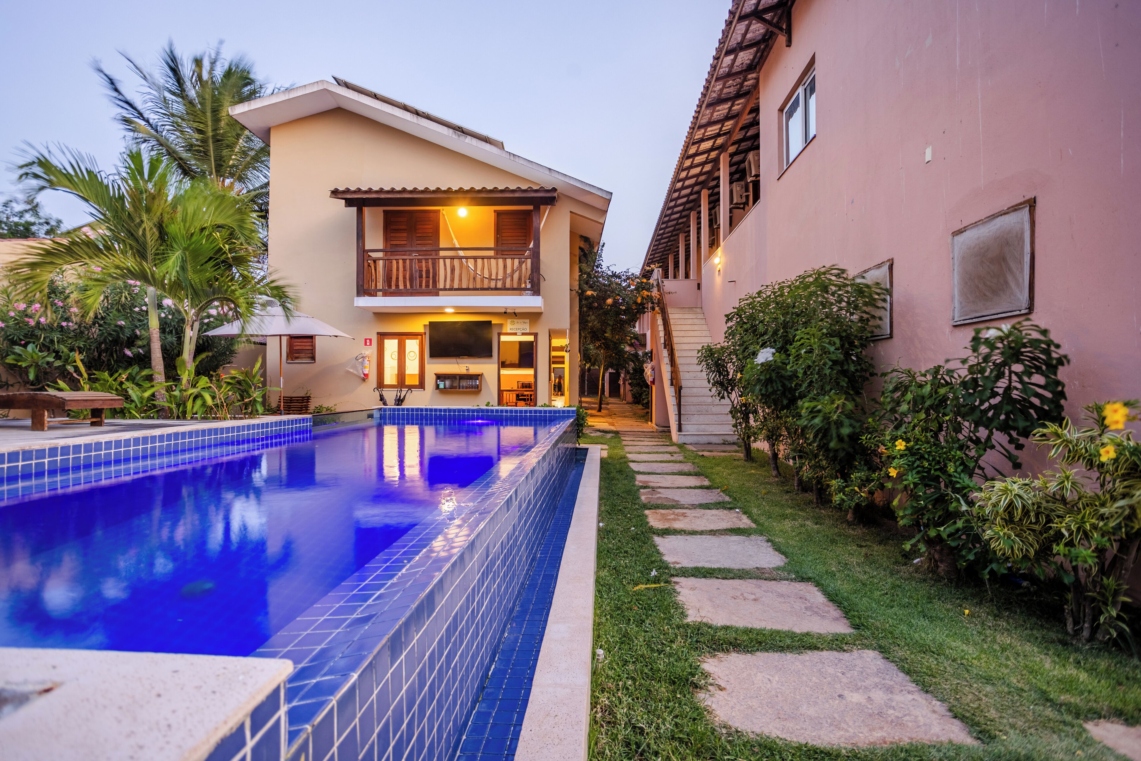 A two-story building with a swimming pool, a balcony, and a garden area.