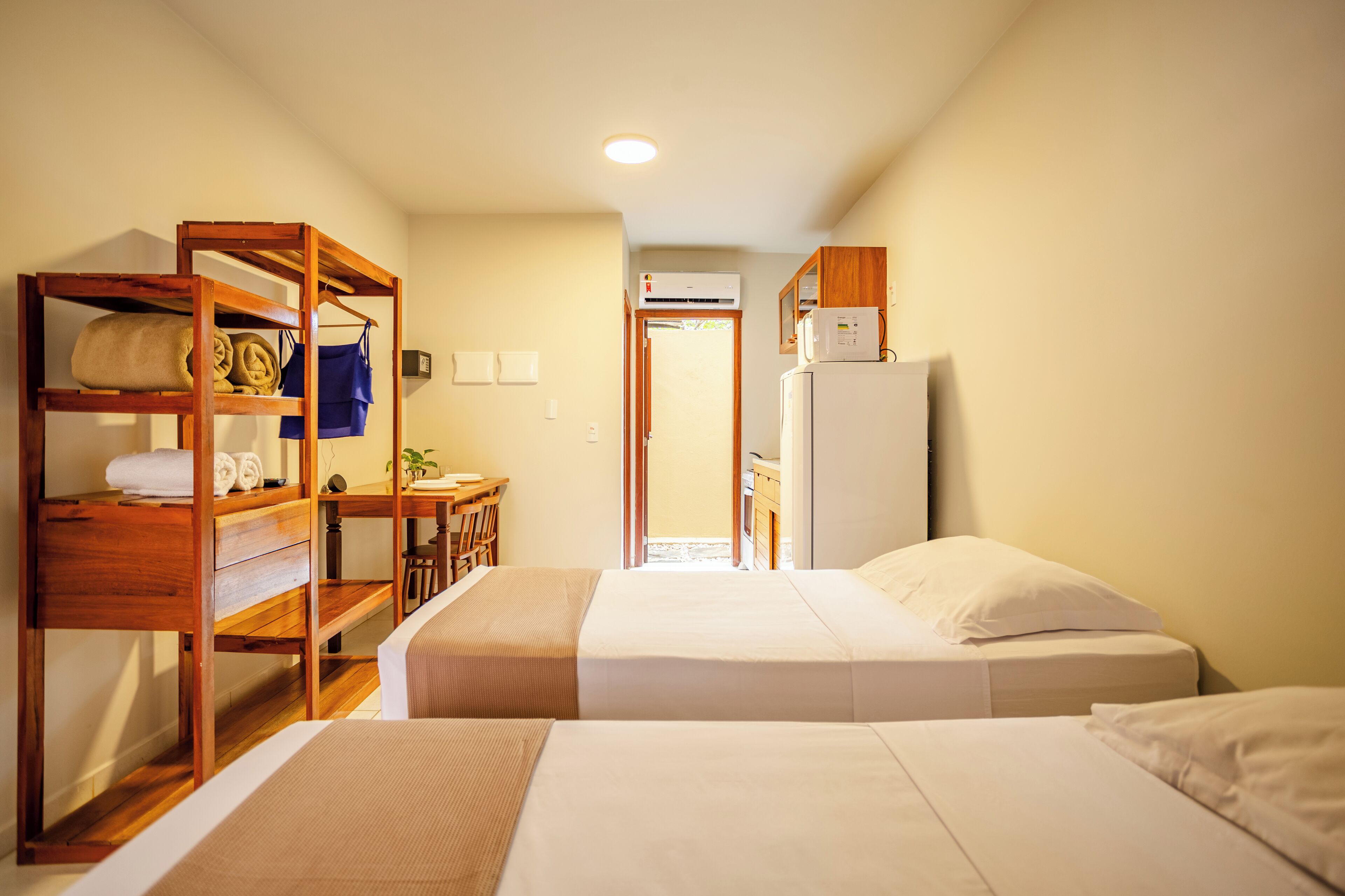 Habitació d'hotel amb dos llits, un armari de fusta, una taula de treball amb cadira i un aparell d'aire condicionat.