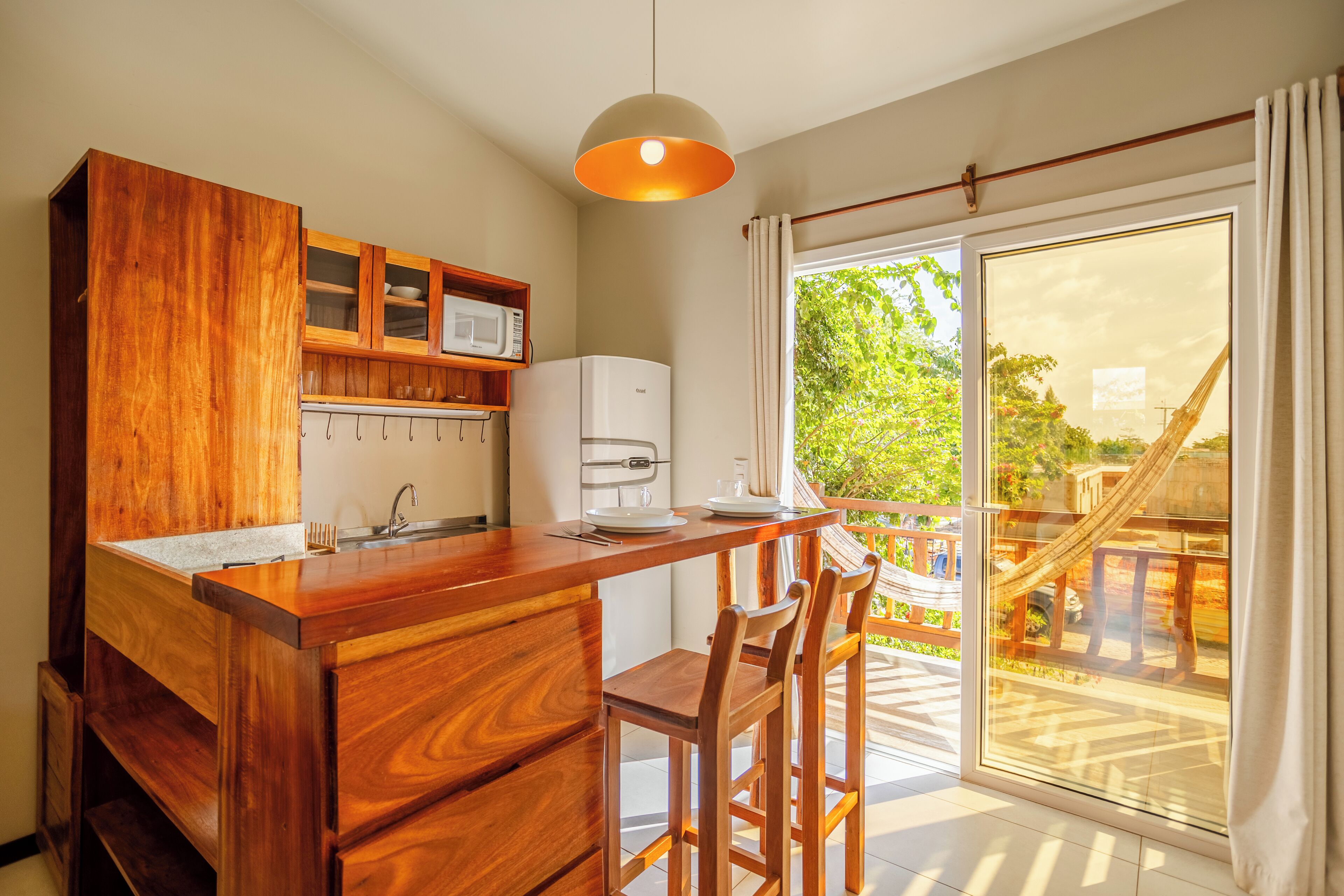 Una cocina con armarios de madera, microondas y cafetera. Hay una zona de comedor con una mesa y sillas.