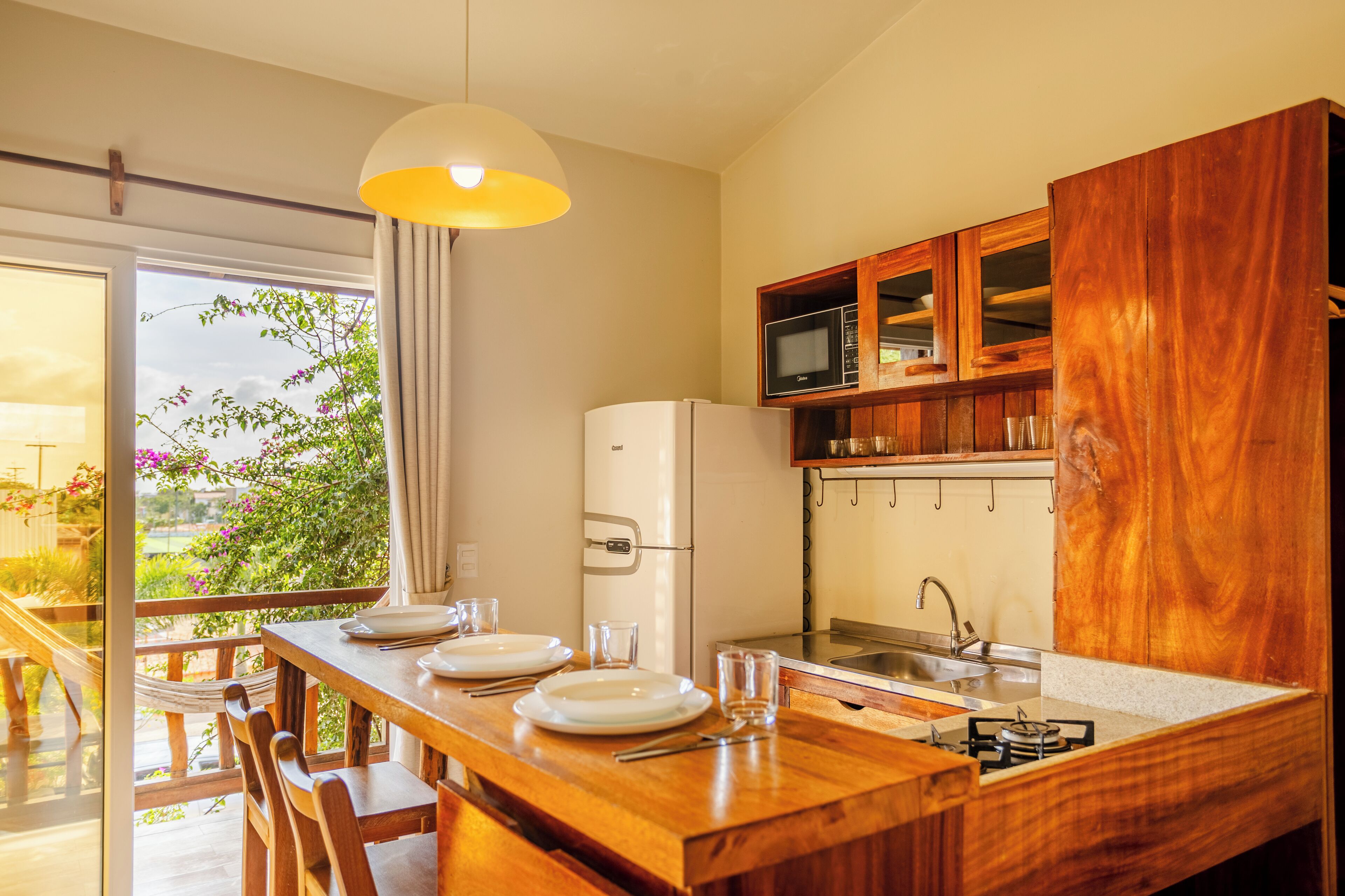 A kitchen with wooden cabinets, a white refrigerator, and a dining area with a table set for two.