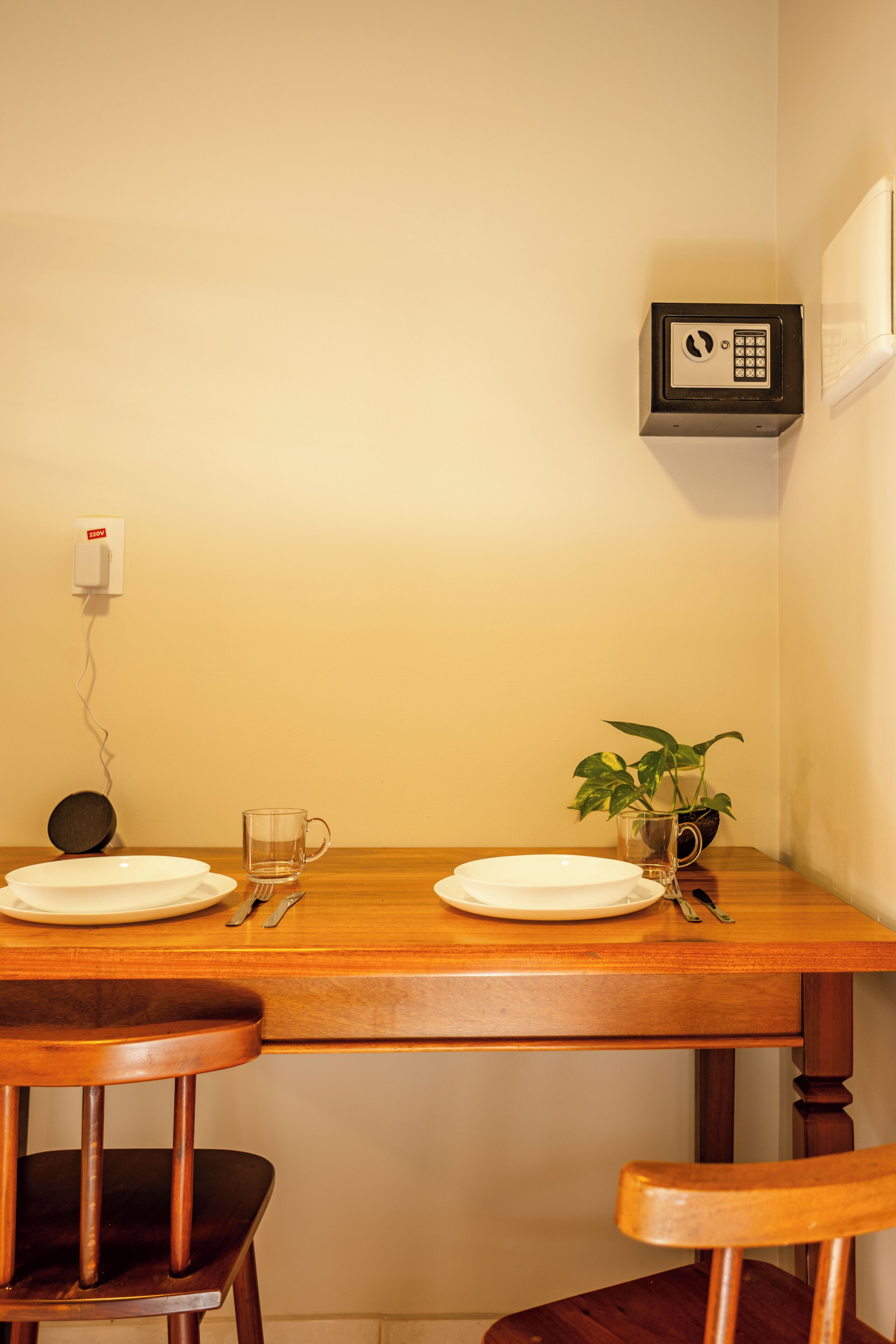 A dining table with plates, cutlery, and a glass mug. There is a potted plant on the table.