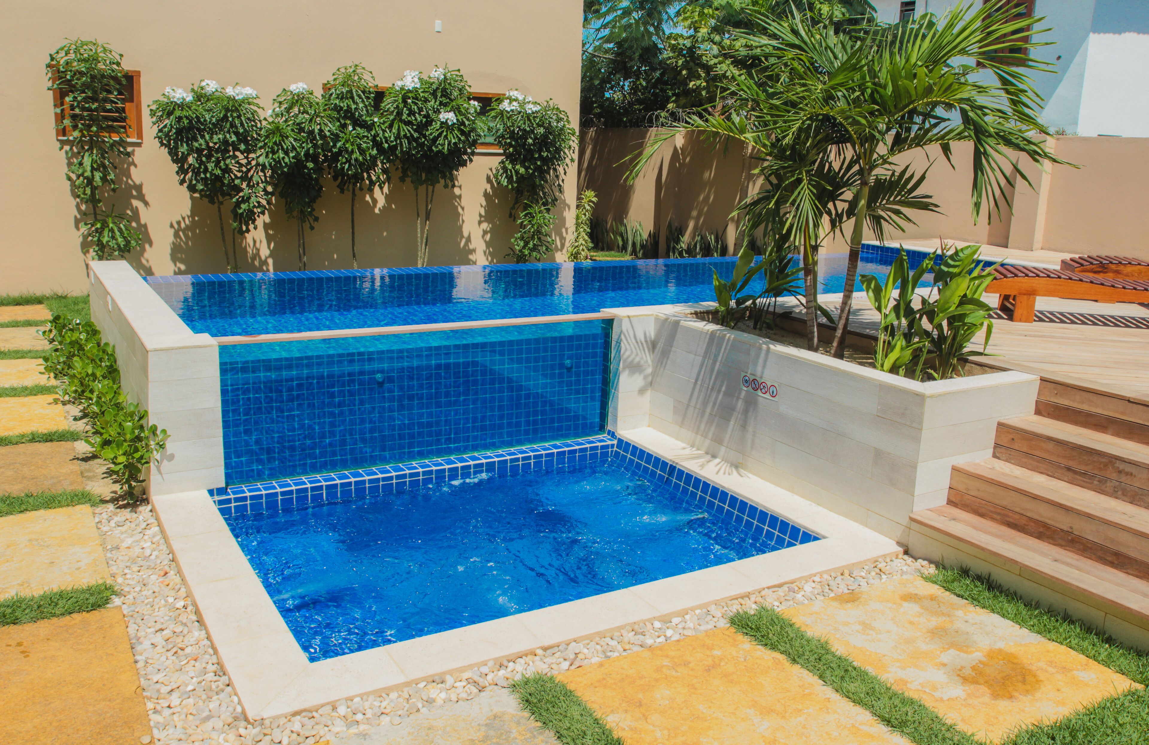A swimming pool with a blue tiled bottom and a small waterfall feature.