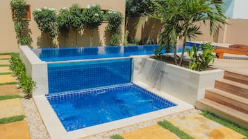 A swimming pool with a blue tiled bottom and a small waterfall feature.